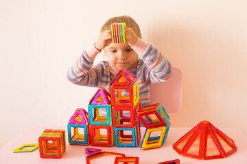 The child assembles a magnetic construction set, builds houses, towers, cars. Educational games....