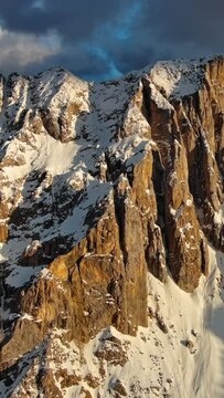 Aerial view of amazing rocky mountains in snow at sunset, Dolomites, Italy, vertical video 4k
