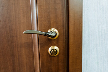 Closeup of a wooden door handle fixture with varnished hardwood and wood stain