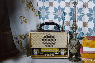 stylish retro radio player stands on a white wooden table near window with old books