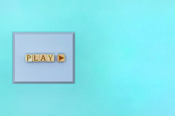 水色の背景の左側にPLAYのアルファベットと再生マークのブロックを並べた四角い立体的な紫のボタン