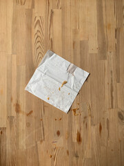 Dirty white square paper napkin with crumbs on a dirty kitchen wooden table
