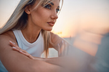 Thoughtful woman captured in the warm light of sunset, displaying introspection and a serene...