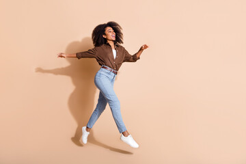 Fototapeta na wymiar Full size photo of adorable woman dressed brown shirt flying run look at proposition empty space isolated on beige color background