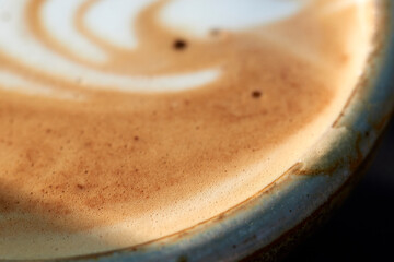 This image captures the essence of a barista’s skill, featuring a close-up of a creamy swirl atop a freshly brewed cappuccino