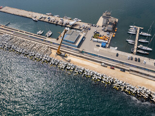 Aerial view of breakwater construction. Crane on a pile of boulders in the sea