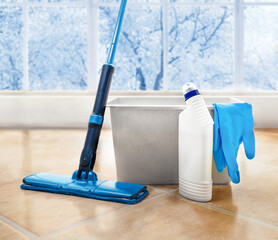 Blue Mop , bucket , spray bottle and gloves are on the tiled floor at room
