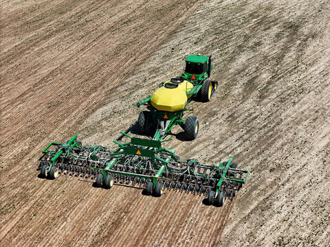 CONWAY, ARKANSAS - USA - April 4, 2024: John Deere 8420T tractor pulling a Deere 1910 air cart with a 68 row Deere 1890 air seeder planting soybeans.