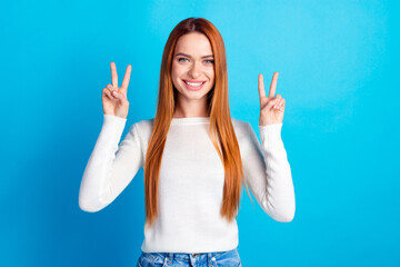 Photo portrait of attractive young woman show v-sign dressed stylish white clothes isolated on blue color background