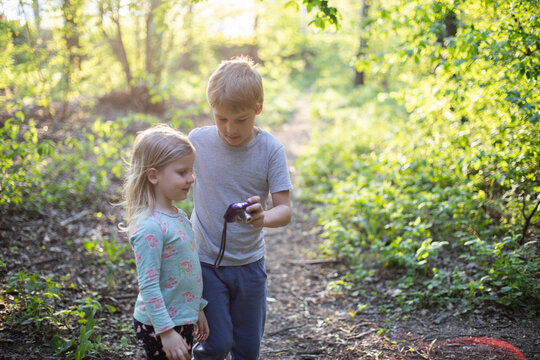 A boy teaches a little girl to take photographs in nature with a camera, child development, photography as a children's hobby
