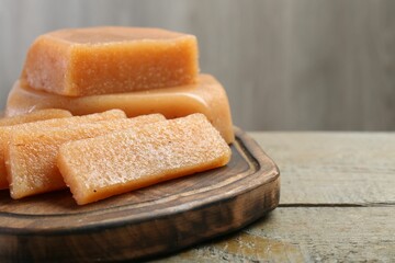Tasty sweet quince paste on wooden table, closeup. Space for text