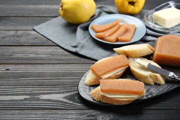 Tasty sandwiches with quince paste served on black wooden table, space for text