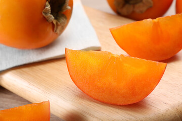 Delicious ripe persimmons on wooden board, closeup