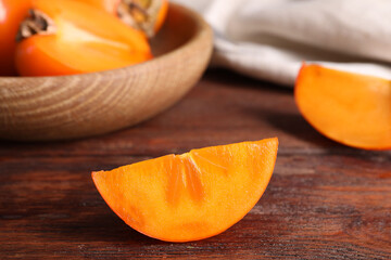 Piece of delicious ripe persimmon on wooden table, closeup