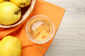 Delicious quince drink in glass and fresh fruits on wooden table, top view. Space for text