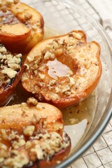 Delicious baked quinces with nuts and honey in bowl on table, closeup
