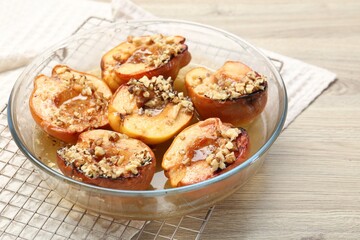 Delicious baked quinces with nuts and honey in bowl on wooden table, closeup