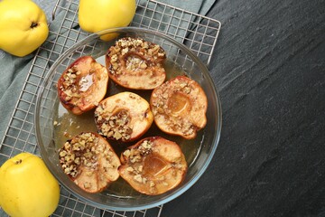Tasty baked quinces with walnuts and honey in bowl on black table, flat lay. Space for text