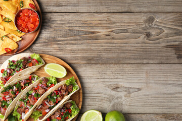 Flat lay composition with delicious tacos on wooden table, space for text