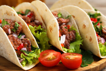 Delicious tacos with meat and vegetables on table, closeup