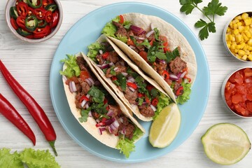 Delicious tacos and ingredients on wooden table, flat lay