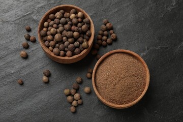 Ground and whole allspice berries (Jamaica pepper) on black table, top view
