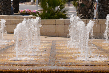 Splashing fountain water a park in city, row of fountains