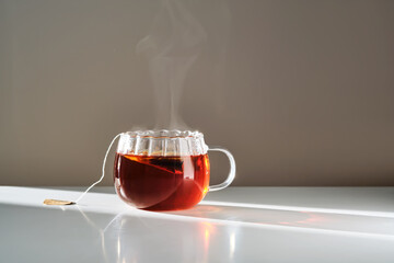 Glass mug with hot black tea on the table.
