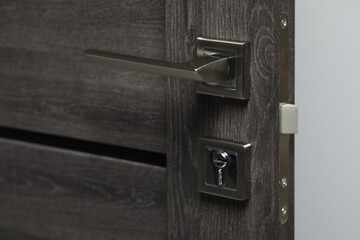 Open wooden door with metal handle, closeup