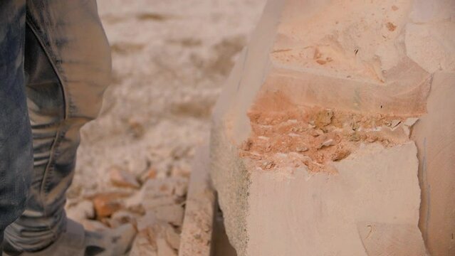 Close-up of male hands in gloves creating a stone sculpture using a chisel and hammer.