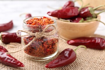 Chili pepper flakes and pods on table, closeup