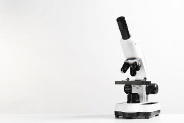 Modern microscope on white table, space for text