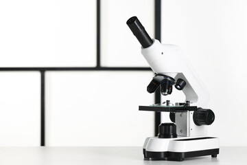 Modern microscope on white table, space for text