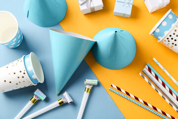 Party hats and other bright decor on color background, flat lay