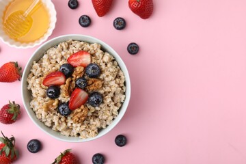 Tasty oatmeal with strawberries, blueberries and walnuts in bowl surrounded by fresh berries on...