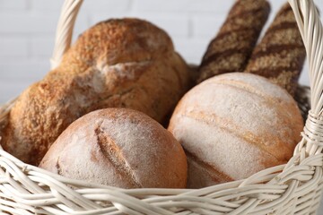 Different types of bread in wicker basket, closeup
