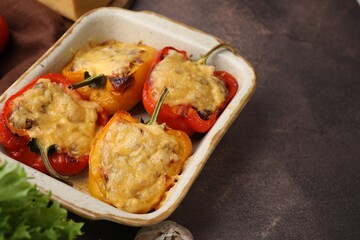 Delicious stuffed peppers in baking dish on brown table, space for text