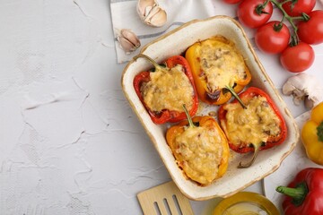 Delicious stuffed peppers in baking dish, spatula and ingredients on white textured table, flat lay. Space for text