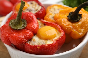 Delicious stuffed peppers with eggs in bowl on table, closeup