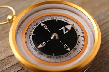 One compass on wooden table, closeup. Navigation equipment