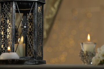 Arabic lantern and burning candles against blurred lights, space for text