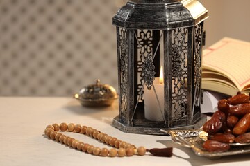 Arabic lantern, Quran, misbaha and dates on white table. Space for text