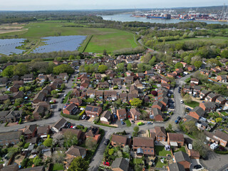 Aerial view of Marchwood residential street with houses and solar farm towards Southampton docks, UK. Southampton container terminal and container ships.