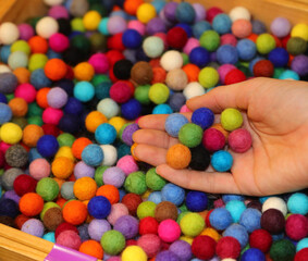 Fototapeta na wymiar hand with many colorful balls made of boiled wool for sale in the hobby shop