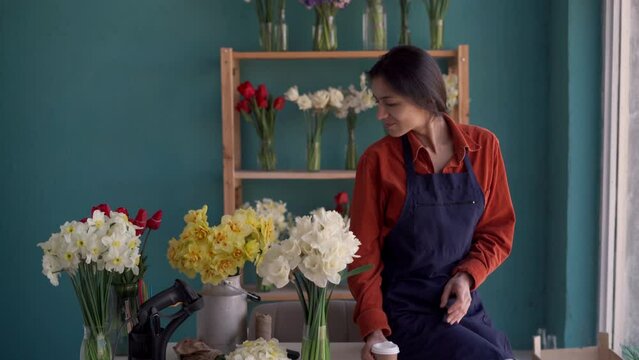 Florist drinking coffee in flower shop workplace. Small business owner in floral store. floristic boutique
