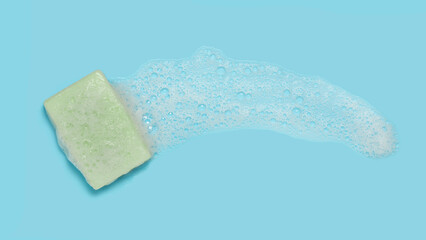 bar of olive oil soap with foam on blue