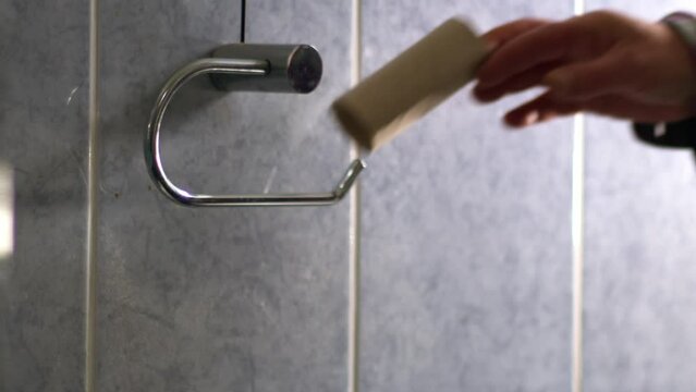 Hand changing toilet roll in bathroom 