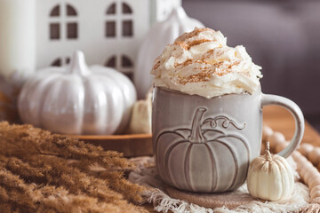 A seasonal drink. Delicious pumpkin latte with whipped cream and cinnamon in a mug on a wooden...