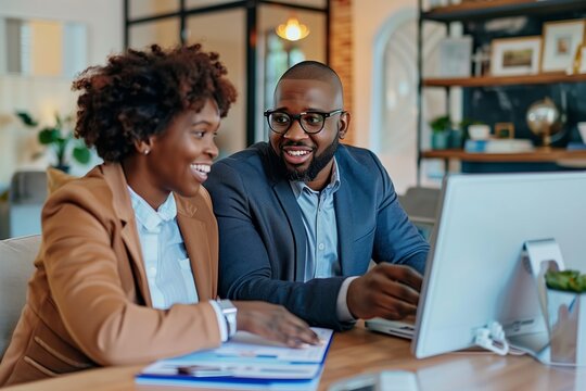 A happy adult black couple looking at their next house on the computer