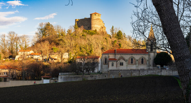 Le château de Busséol, l'église Saint-André et les reliefs volcaniques du Puy-de-Dôme baignés par la lumière du crépuscule